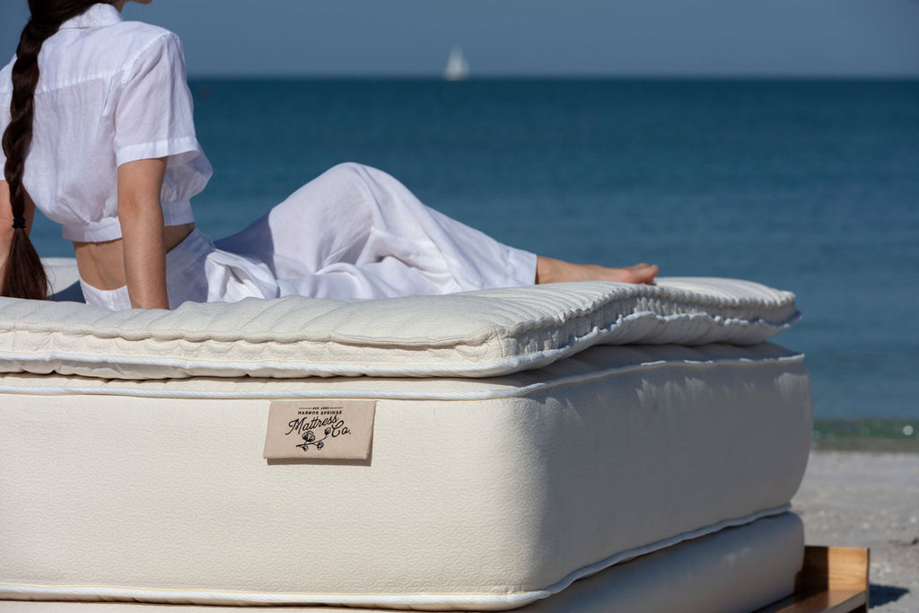 Picture of the Trillium Mattress from Harbor Springs Mattress Co with a woman resting and looking at the gulf coast in Naples Florida.